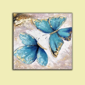 May include: Two blue butterflies with gold accents painted on a textured canvas background.