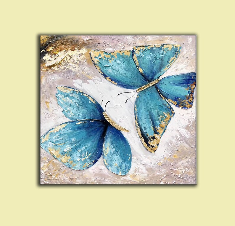 May include: Two blue butterflies with gold accents painted on a textured canvas background.