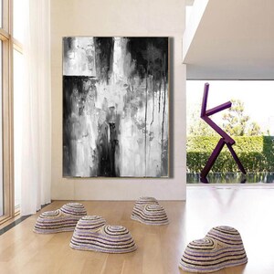 Puede incluir: Pintura abstracta en blanco y negro con pinceladas gruesas y gotas de pintura. La pintura est&aacute; colgada en una pared blanca en una sala de estar moderna.