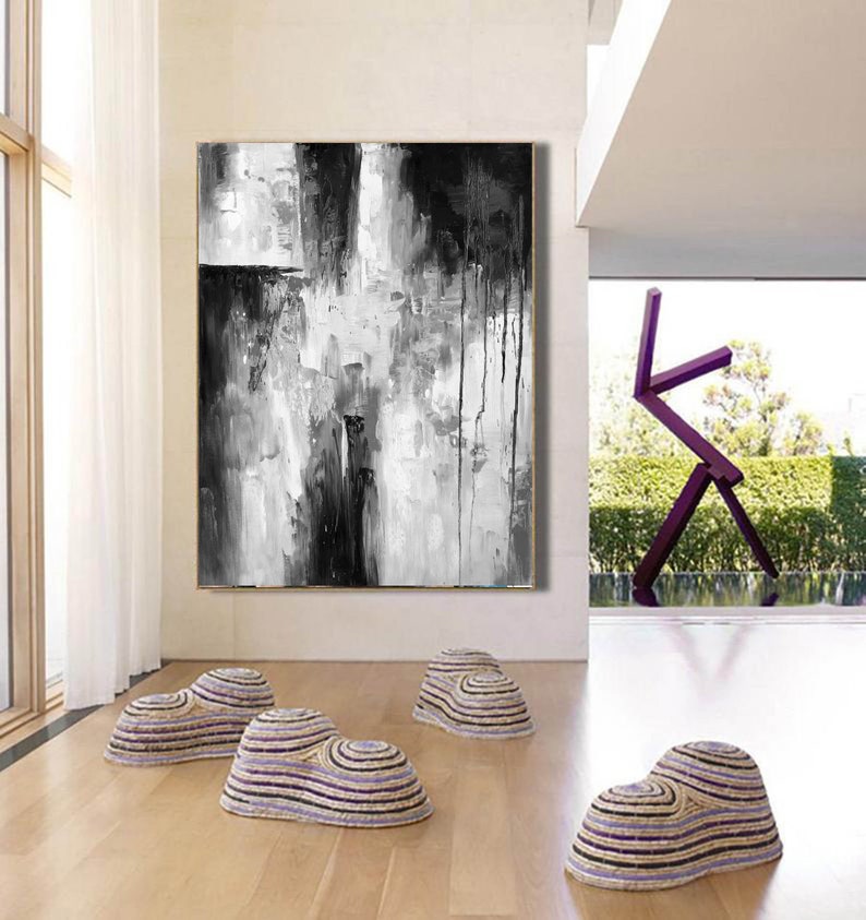 Puede incluir: Pintura abstracta en blanco y negro con pinceladas gruesas y gotas de pintura. La pintura est&aacute; colgada en una pared blanca en una sala de estar moderna.