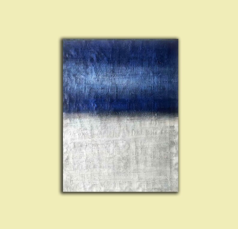 Puede incluir: Pintura abstracta con un esquema de color horizontal azul y blanco. La mitad superior de la pintura es de un azul profundo con una superficie texturizada. La mitad inferior es de un blanco m&aacute;s claro con una superficie texturizada.