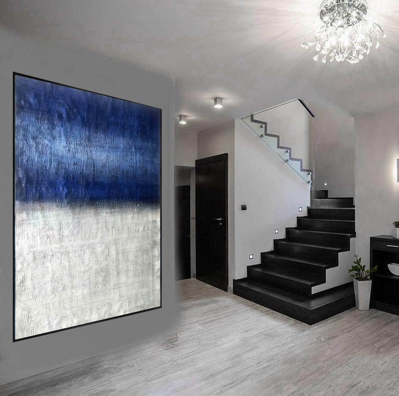 Puede incluir: Pintura abstracta con un esquema de color azul y blanco. La pintura est&aacute; colgada en una pared en una casa moderna con una escalera en el fondo.