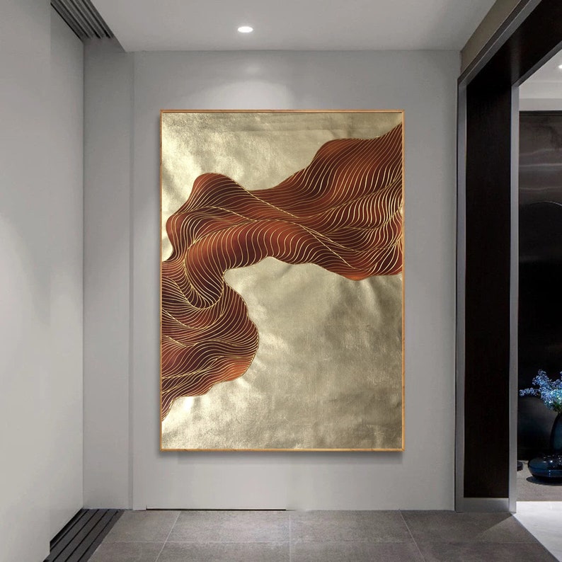 May include: Abstract wall art featuring a flowing, wavy design in shades of brown and gold. The artwork is framed and has a textured, metallic finish.