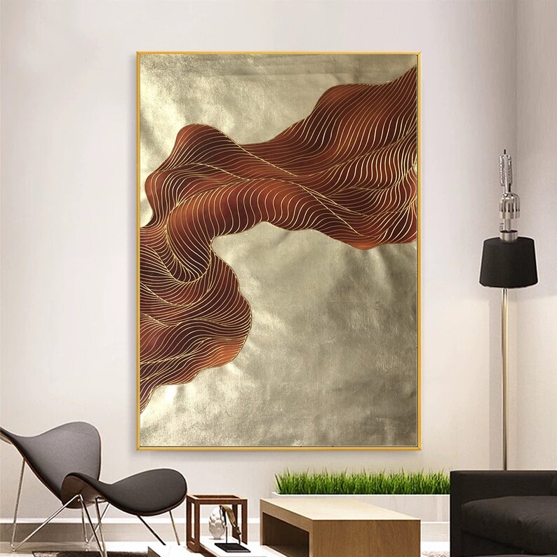 May include: Abstract wall art featuring a gold and brown wave design on a silver background. The painting is framed in a gold frame.