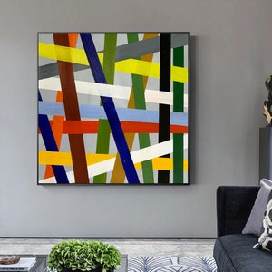 May include: Abstract painting with a geometric design featuring intersecting lines in various colors, including yellow, red, blue, green, white, and brown.