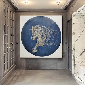 May include: A large abstract painting of a gold horse on a blue background. The horse is made up of small gold dots and is in a running pose. The painting is framed in a white frame.