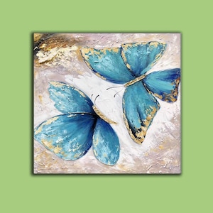 May include: A painting of two blue butterflies with gold accents on a white background.
