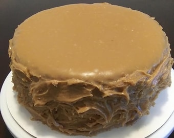 Puede incluir: Un pastel redondo cubierto con una gruesa capa de glaseado de caramelo marrón. El glaseado tiene un patrón de remolino.