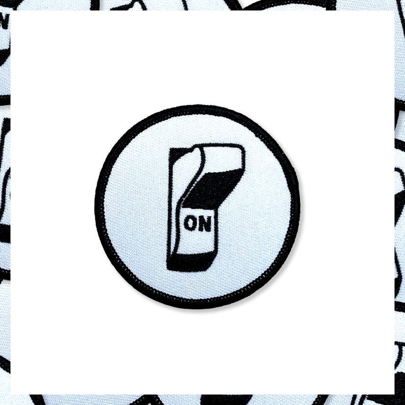 May include: A circular patch with a black border and a white background. The patch features a black and white illustration of a switch in the "ON" position. The word "ON" is printed in black.