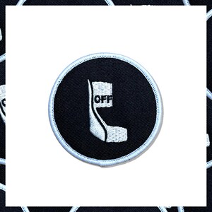May include: A circular black patch with a white and light blue border. The patch features a white graphic design with the word "OFF" in white text.