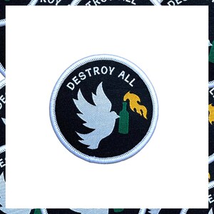 May include: Circular patch with the words "DESTROY ALL" in white, arched around the top. A white dove holds a green bottle with a yellow flame. The patch has a black background and a white border.