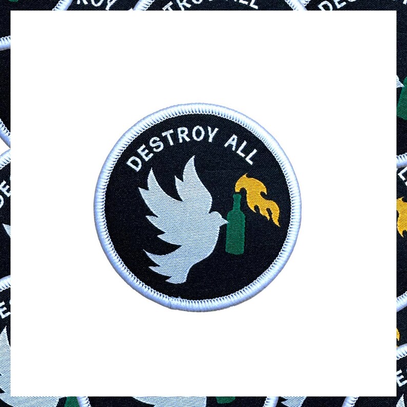 May include: Circular patch with the words "DESTROY ALL" in white, arched around the top. A white dove holds a green bottle with a yellow flame. The patch has a black background and a white border.
