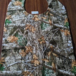 May include: A large, brown, green, and white camouflage fabric bib with the word "LARGE" printed on it.