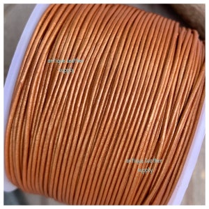 May include: A spool of copper-colored leather cord. The cord is tightly wound and appears smooth with a slight sheen. The text "antique leather supply" is printed on the spool.