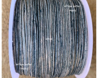 May include: A spool of gray leather cord with a white label that reads "antique leather supply".