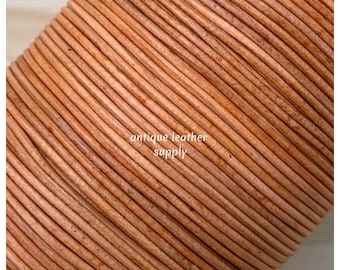 May include: Close-up of a roll of light brown leather cord. The cord is tightly wound and has a smooth, slightly textured surface. The text "antique leather supply" is visible on the cord.