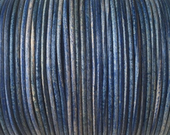 May include: Close-up of a spool of blue and white leather cord. The cord is tightly wound and has a textured surface.