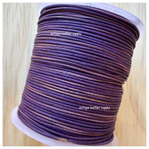 May include: A spool of purple leather cord, wound tightly. The cord is a deep purple color with a slight sheen. The text "antique leather supply" is printed on the spool.
