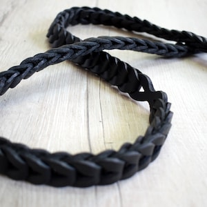May include: A black leather braided strap with a woven design.
