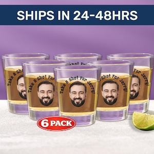 Pode incluir: Seis copos de shot transparentes cheios de um líquido dourado, cada um com o rosto de um homem sorridente e o texto "Take A Shot For Jerry!". Uma fatia de limão está ao lado. A imagem inclui o texto "6 PACK".