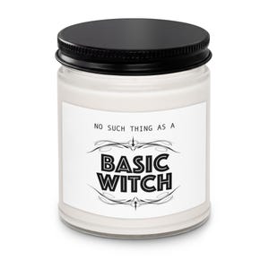 May include: A clear glass candle jar filled with white wax and topped with a black metal lid. The white label features the black text "NO SUCH THING AS A BASIC WITCH" in a bold, stylized font, accented by decorative black flourishes above and below.