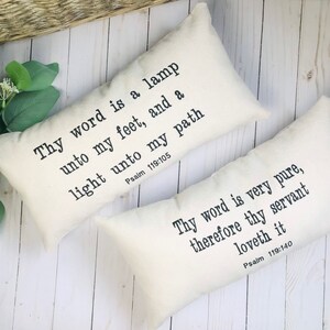 Puede incluir: Dos cojines decorativos rectangulares de color crema con texto negro. Uno dice "Thy word is a lamp unto my feet, and a light unto my path Salmo 119:105". El otro dice "Thy word is very pure, therefore thy servant loveth it Salmo 119:140."