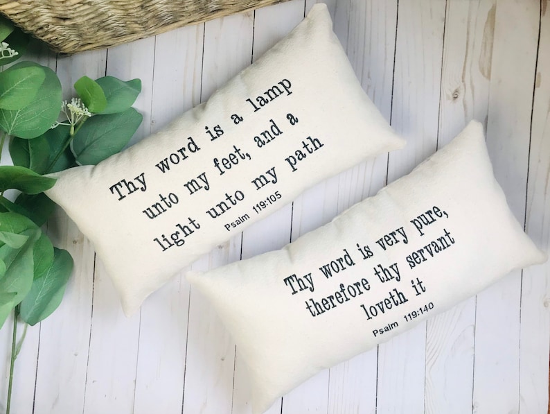 Puede incluir: Dos cojines decorativos rectangulares de color crema con texto negro. Uno dice "Thy word is a lamp unto my feet, and a light unto my path Salmo 119:105". El otro dice "Thy word is very pure, therefore thy servant loveth it Salmo 119:140."