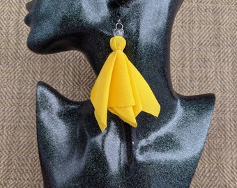 May include: Yellow fabric tassel earrings with a clear bead accent.