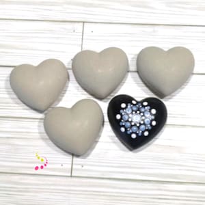 May include: Five heart-shaped stones, four are gray and one is black with a white and blue mandala design.