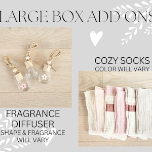 May include: Three glass fragrance diffusers shaped like light bulbs with a wooden top and string hanging from the top. The diffusers are on a light brown wooden surface. The text "FRAGRANCE DIFFUSER SHAPE & FRAGRANCE WILL VARY" is below the diffusers.  A set of six cozy socks in pink and beige are on a light brown wooden surface. The text "COZY SOCKS COLOR WILL VARY" is above the socks.