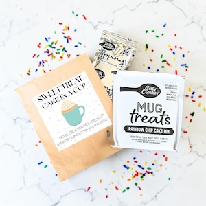 Pu&ograve; includere: Immagine di miscele per dolcetti in tazza Betty Crocker e bustine di topping. La confezione include "Sweet Treat Cake in a Cup" e "Mug Treats Rainbow Chip Cake Mix" con confettini colorati.