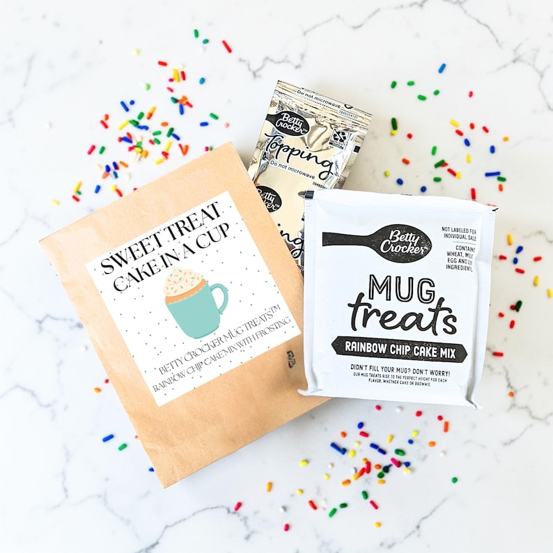 Pu&ograve; includere: Immagine di miscele per dolcetti in tazza Betty Crocker e bustine di topping. La confezione include "Sweet Treat Cake in a Cup" e "Mug Treats Rainbow Chip Cake Mix" con confettini colorati.