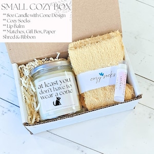 Pu&ograve; includere: Una piccola scatola regalo accogliente contenente una candela da 227g con design a cono, calzini accoglienti, balsamo per le labbra, fiammiferi, confezione regalo, carta sminuzzata e nastro. La candela ha un messaggio umoristico e una sagoma di gatto.