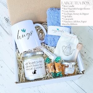 Pu&ograve; includere: Una grande scatola da t&egrave; con una tazza bianca con la scritta "hugs", un asciugamano blu, una candela, bustine di t&egrave;, miele, burrocacao, caramelle e calzini accoglienti. La candela dice "at least you don't have to wear a cone".