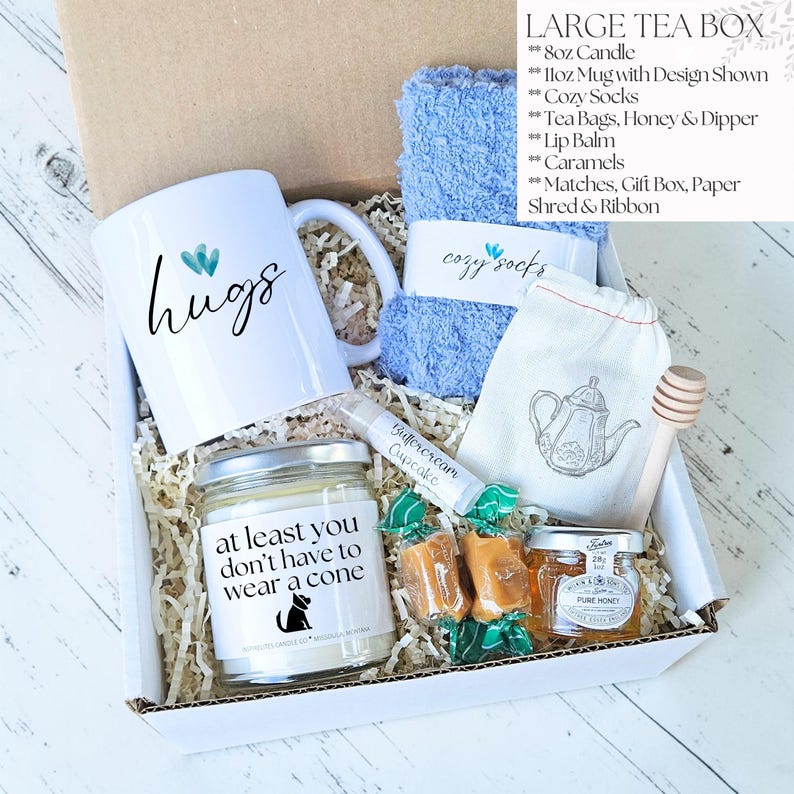 Pu&ograve; includere: Una grande scatola da t&egrave; con una tazza bianca con la scritta "hugs", un asciugamano blu, una candela, bustine di t&egrave;, miele, burrocacao, caramelle e calzini accoglienti. La candela dice "at least you don't have to wear a cone".