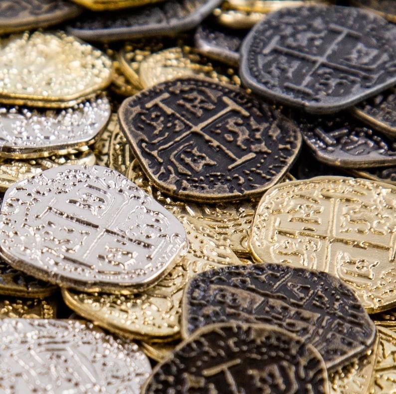 May include: A close-up shot of a pile of antique-style coins in various metallic finishes, including gold, silver, and bronze. The coins feature intricate embossed designs, with a prominent cross motif visible on several. The overall theme suggests treasure or historical artifacts.