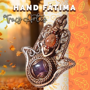 Peut inclure: Un charme de main de Hamsa en fil de cuivre avec une améthyste violette et une pierre de soleil. Le charme est sur un fond de feuilles d'automne.