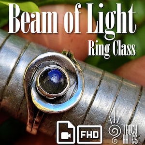 Könnte beinhalten: Ein silberner Ring mit einem dunkelblauen Edelstein in der Mitte, eingefasst in einem spiralförmigen Design. Der Ring befindet sich auf einer Metalloberfläche. Der Text "Beam of Light Ring Class" und "Tracy Artes" ist zu sehen.