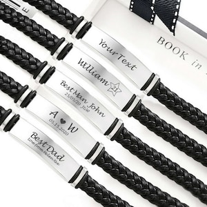 May include: Close-up of several black braided leather bracelets with silver rectangular nameplates. Each plate has personalized text, including names, dates, and phrases like "Best Man" and "Best Dad". The bracelets are displayed on a white surface.