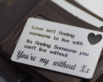 May include: A silver metal card with the text "Love isn't finding someone to live with. Its finding Someone you can't live without. You're my without Xx" and a heart symbol. The card rests on a brown leather wallet.