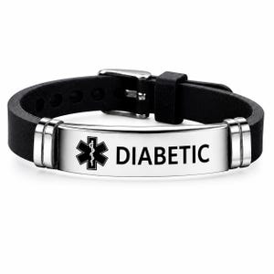 Könnte beinhalten: Ein schwarzes Silikon-Armband für medizinische Notfälle mit einer polierten, silberfarbenen Metallplatte. Die Platte zeigt ein schwarzes Stern des Lebens-Symbol und das Wort DIABETIC in fetten schwarzen Großbuchstaben. Mit Metallschnalle.
