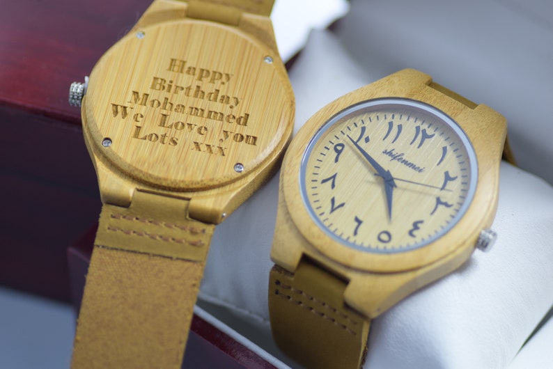 May include: Two bamboo watches with leather straps. One watch has Arabic numerals and the brand name "shifenmei" on the face. The other watch has the inscription "Happy Birthday Mohammed We Love you Lots xxx" engraved on the back.