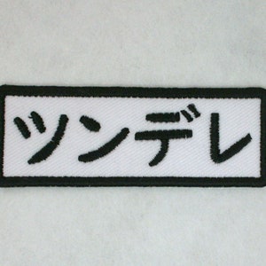 May include: White rectangular patch with black embroidered Japanese text that reads "シンデレ" (Cinderella).