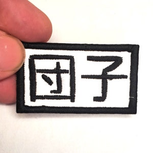 May include: A white embroidered patch with black stitching. The patch is rectangular and has the Chinese characters "国子" (Guó Zǐ) embroidered on it.