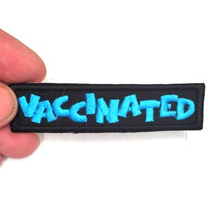 May include: A black fabric patch with the word "VACCINATED" embroidered in blue.