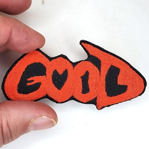 May include: A red and black embroidered patch with the word "GOOD" in a stylized font.