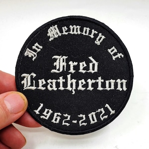 以下が含まれることがあります： 「In Memory of Fred Leatherton 1962-2021」というテキストが書かれた黒と白の刺繍パッチ。