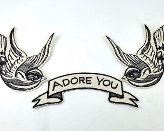May include: Two black embroidered swallow bird patches with a white banner that reads "ADORE YOU".