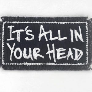 May include: Black embroidered patch with white stitching. The patch reads "It's All in Your Head".