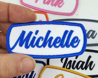 Op de afbeelding: Blauwe geborduurde patch met een witte achtergrond en de naam "Michelle" in blauwe cursieve letters.